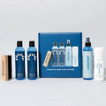 Collection of shoe care products including bottles and a brush on a gray background