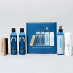 Collection of shoe care products including bottles and a brush on a gray background