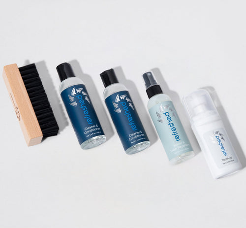 Set of cleaning products including bottles and a brush on a light gray background