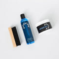 Set of shoe care products including a bottle, brush, and container on a white background