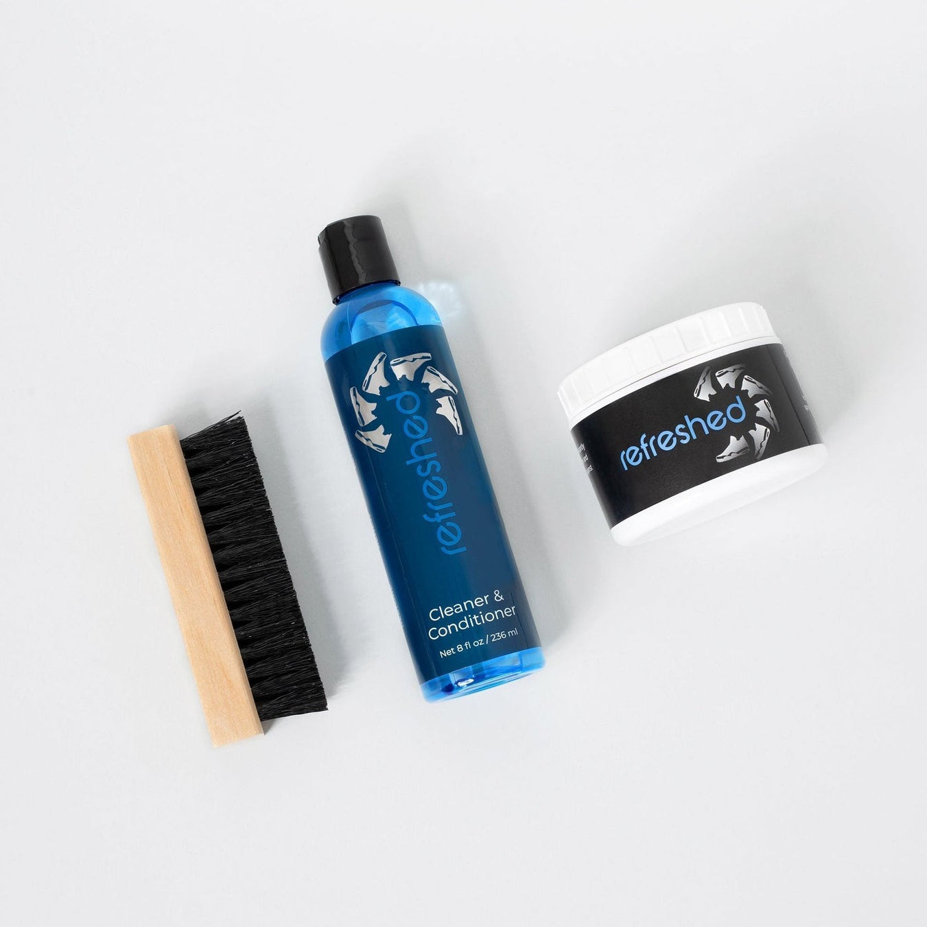 Set of shoe care products including a bottle, brush, and container on a white background